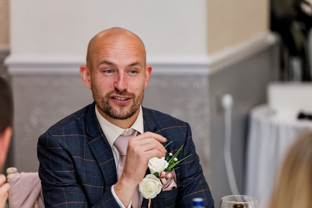Formal wedding attire with white rose boutonniere and navy suit details.