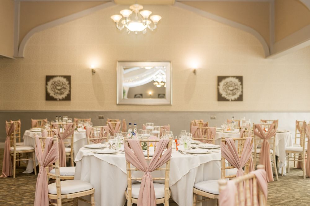 Elegant wedding reception venue with pink and white decor and round tables.