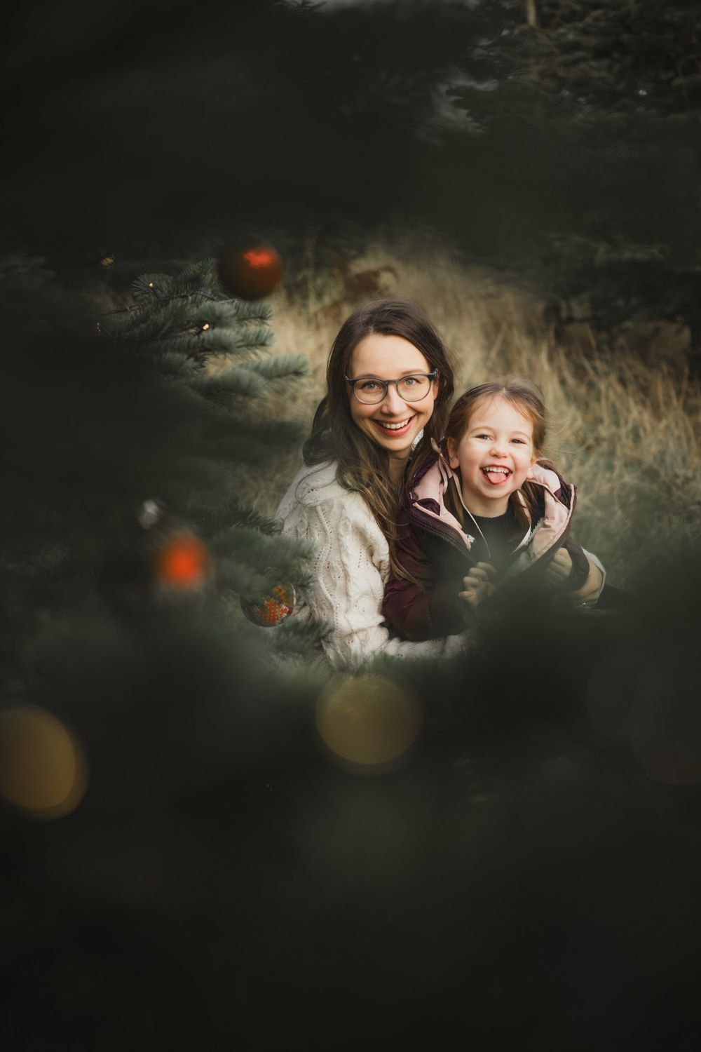 A joyful moment captured through natural foliage in moody lighting with bokeh effects in the foreground.