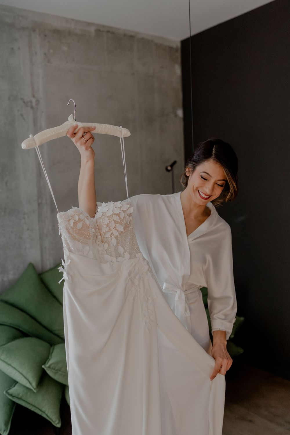 Die Braut schaut sich beim Getting Ready ihr Brautkleid an und freut sich das Kleid gleich anzuziehen und freut sich auf die Hochzeitsfeier.