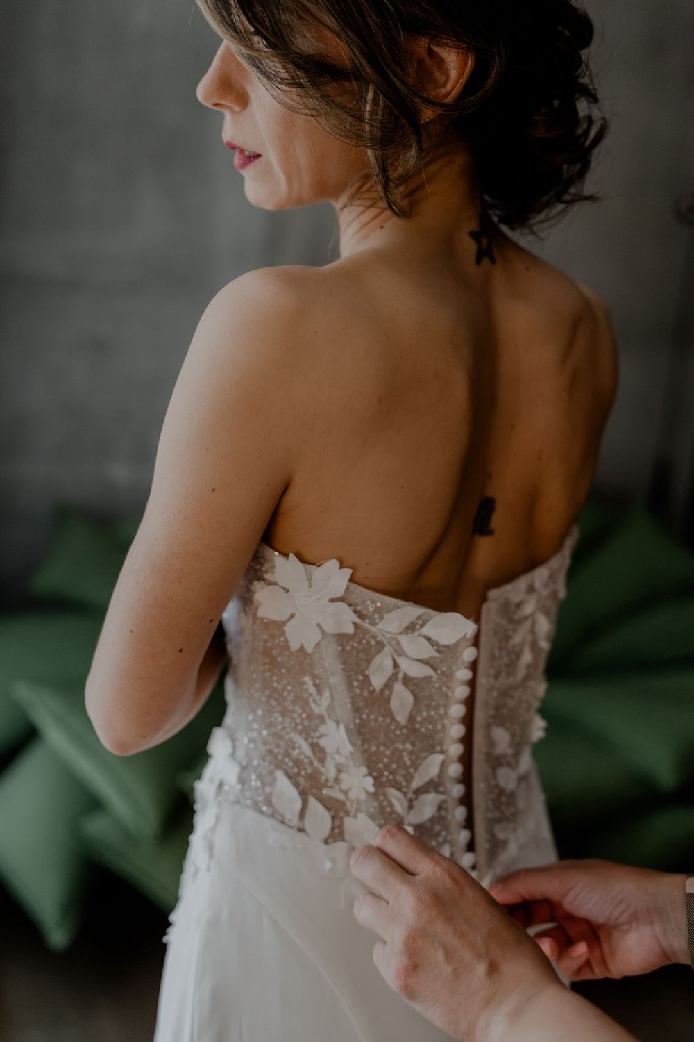 Im KPM Hotel beim Getting Ready hilft die Stylisten der Braut beim Anziehen ihres Brautkleid. Sie macht den Reisverschluss zu.
