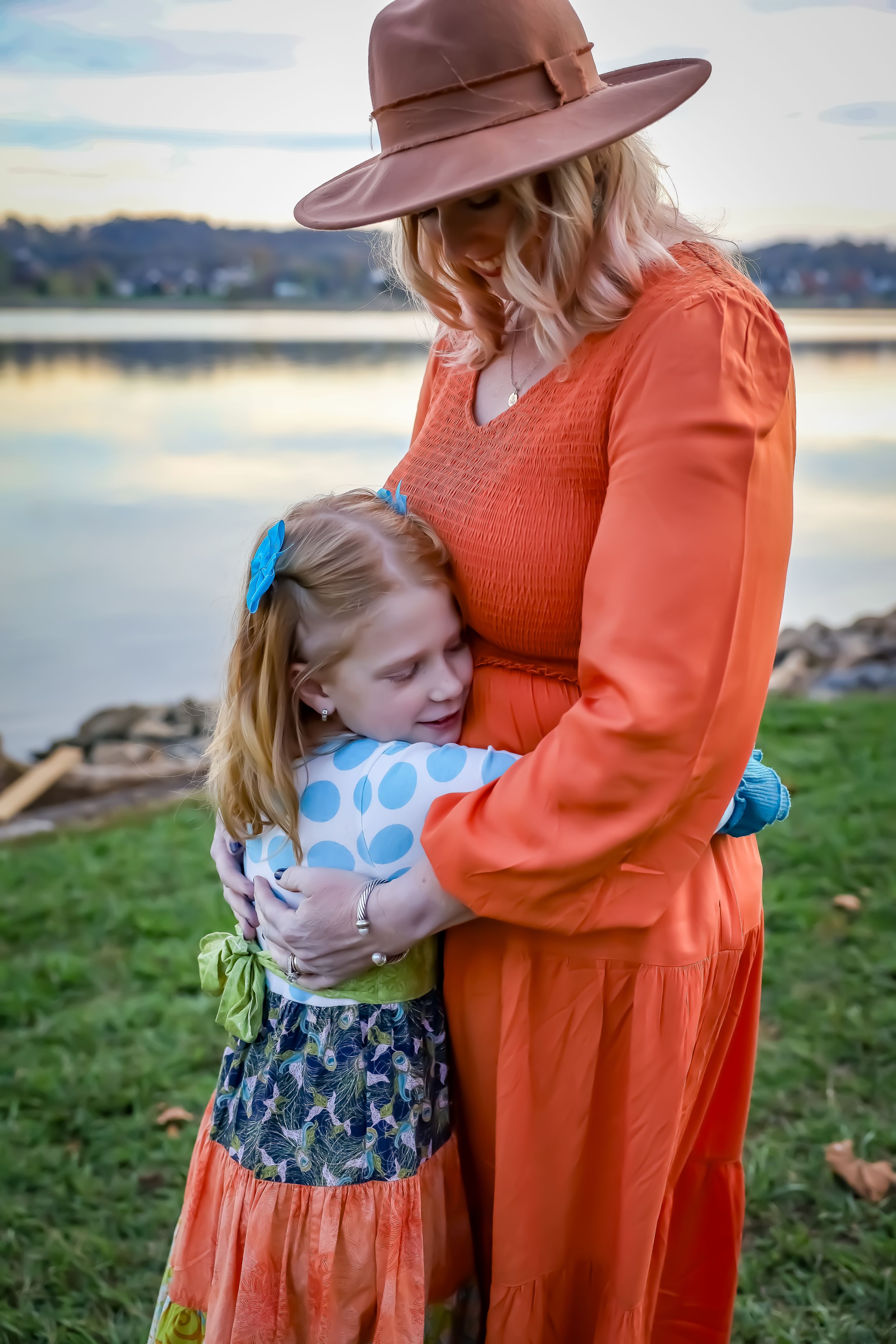 A tender moment between parent and child in matching coral outfits by the water.