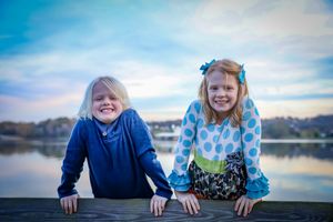 Children playing and smiling along a waterfront during sunset.