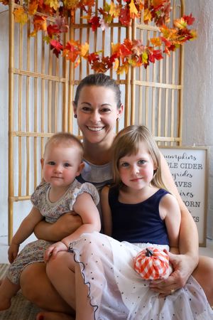Fall-themed family photo session with autumn leaf decorations and pumpkin props.