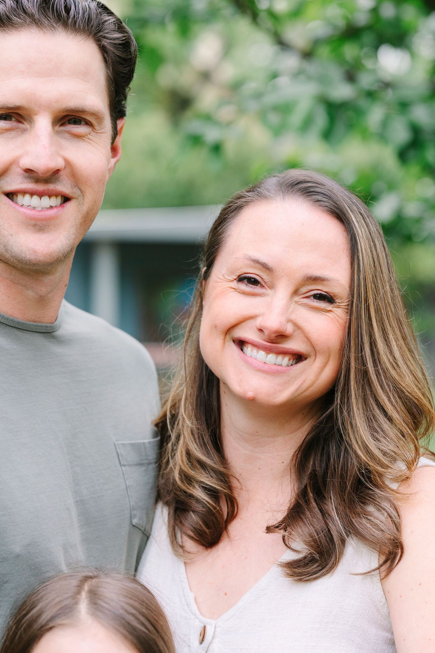 A close up portrait of a couple smiling together outdoors.
