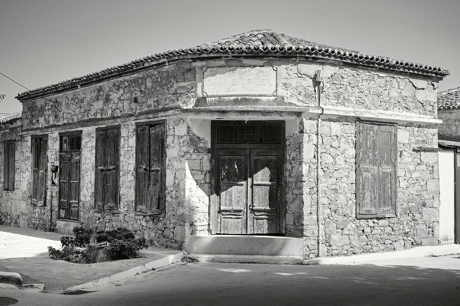 A series of abandoned rural buildings in black and white under dramatic cloudy skies.