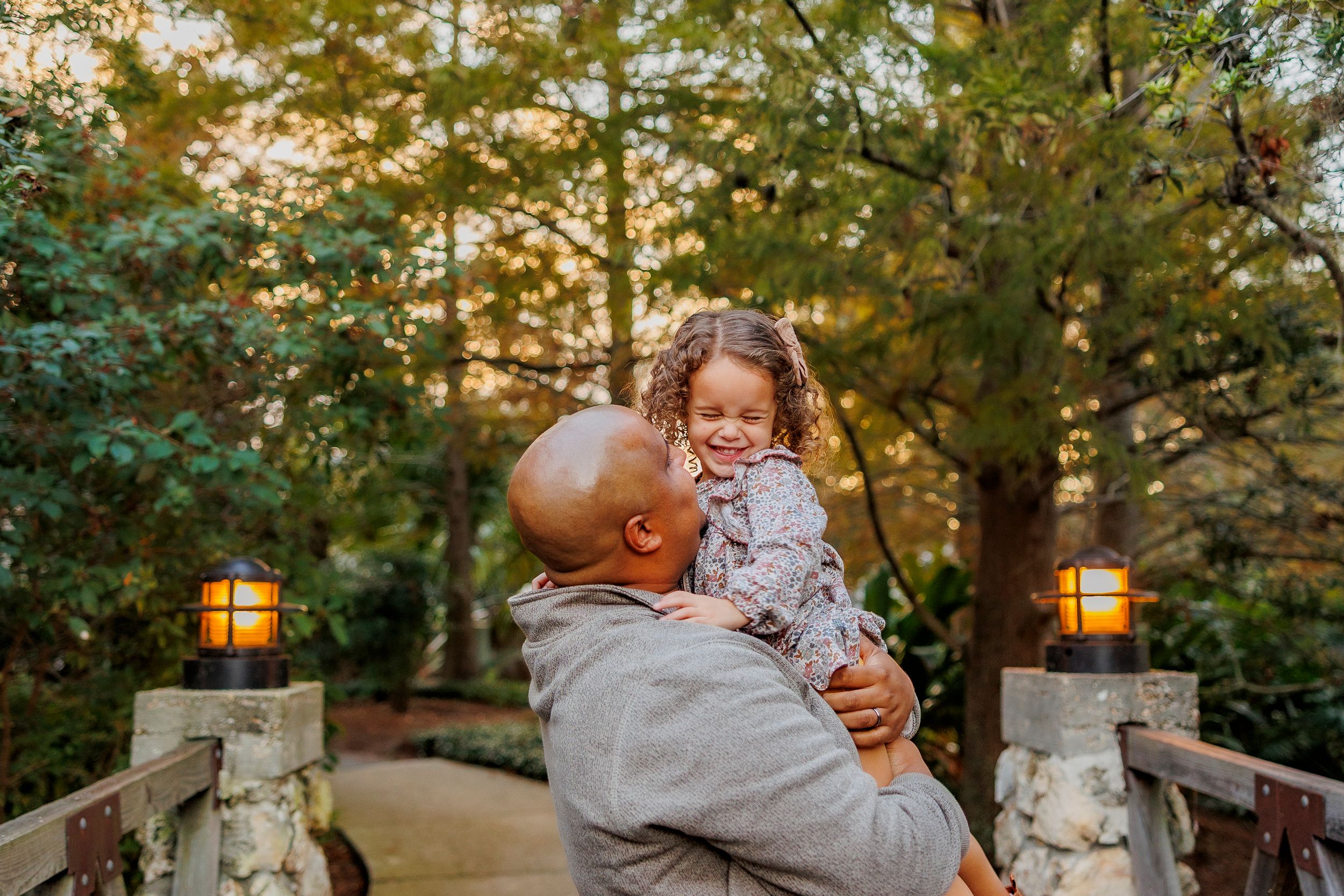 Family enjoying a warm sunset moment together in a park setting with golden sunlight filtering through trees.