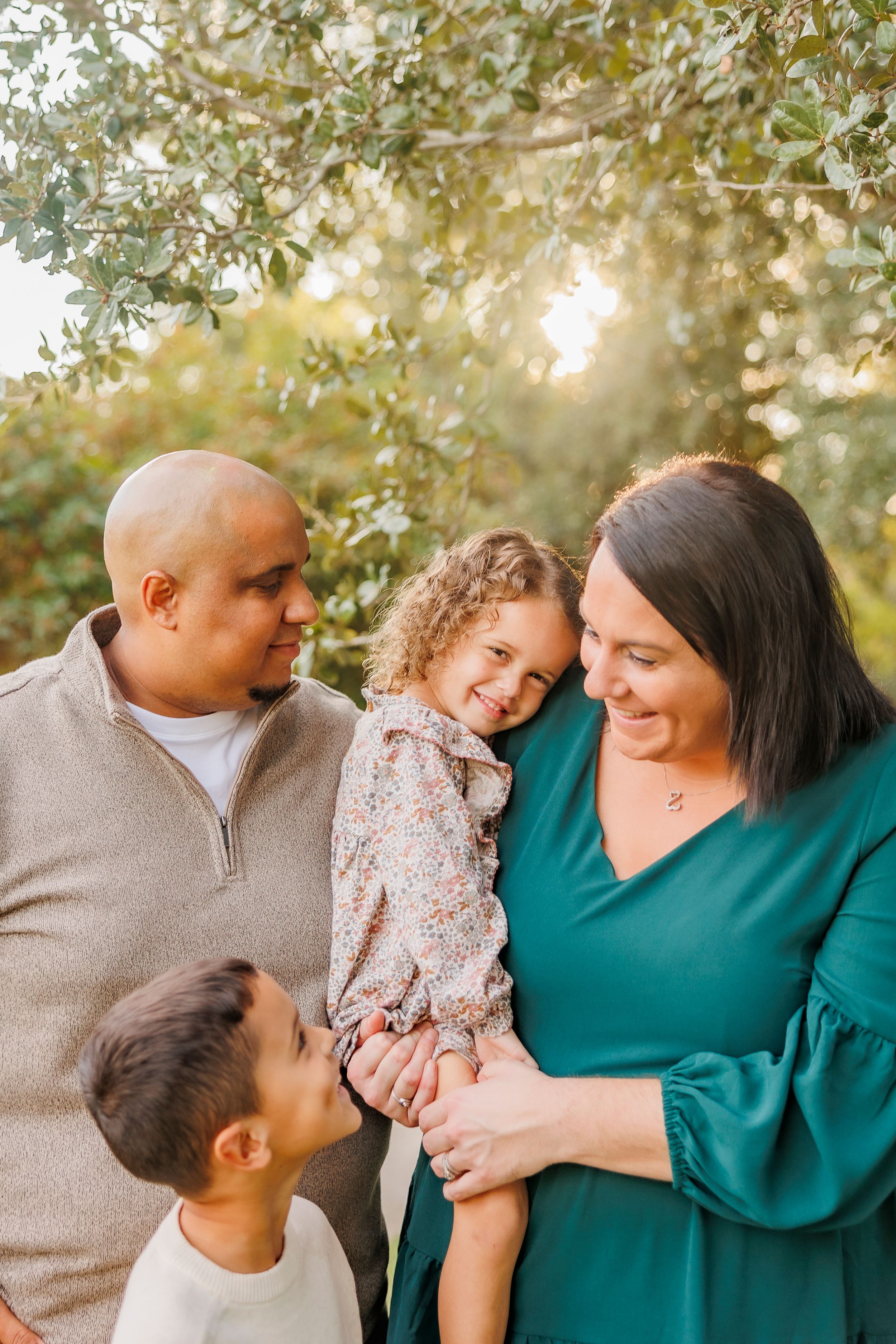 Family shares tender moments together outdoors during sunset photo session.