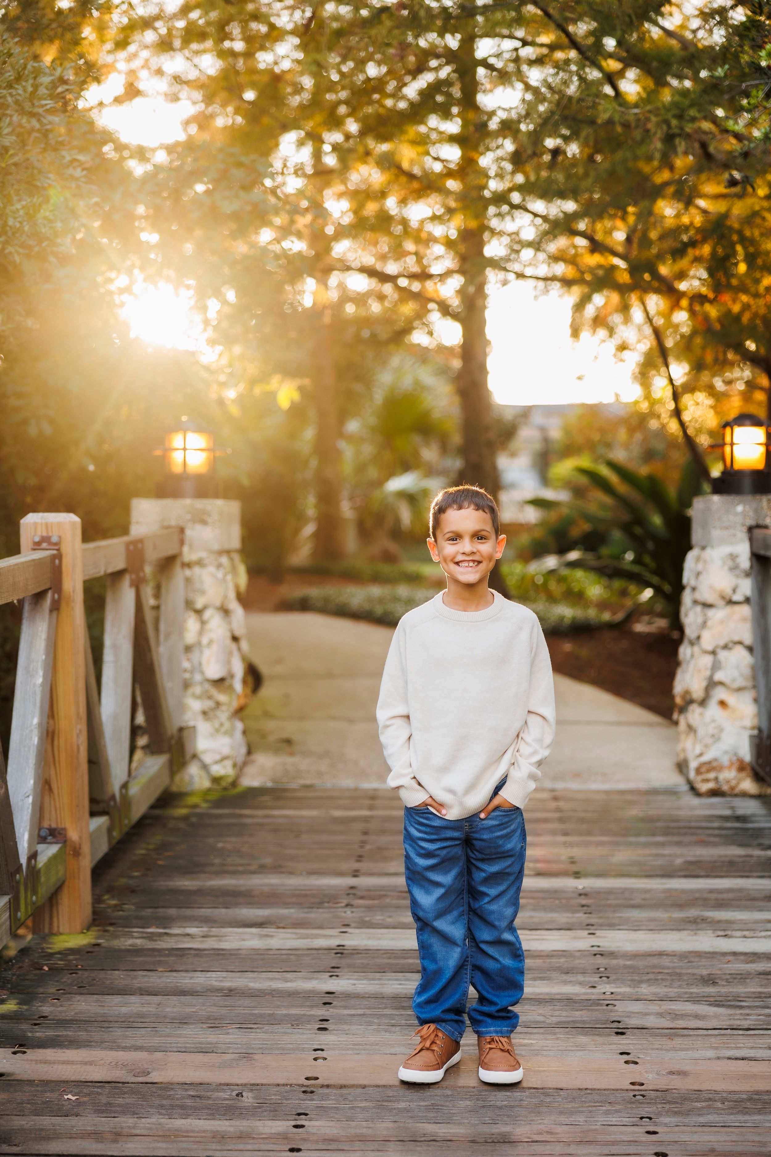 A series of five connected photos showing a young child in jeans and white shirt on a wooden bridge at sunset.