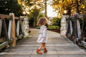 Feet walking along a rustic wooden bridge pathway at sunset.