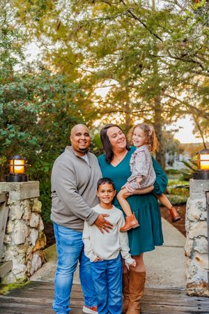 Family poses together by stone wall during golden hour outdoor photo session.