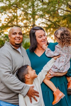 Family embraces and laughs together during outdoor autumn photo session.