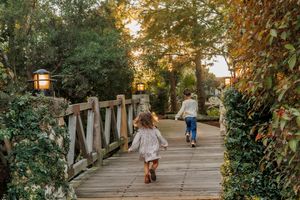 People walking along a garden pathway with hanging lanterns at sunset creating a romantic atmosphere.