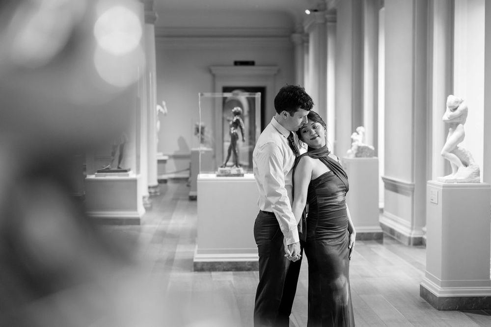 A romantic black and white scene captured in a bright hallway with soft lighting.