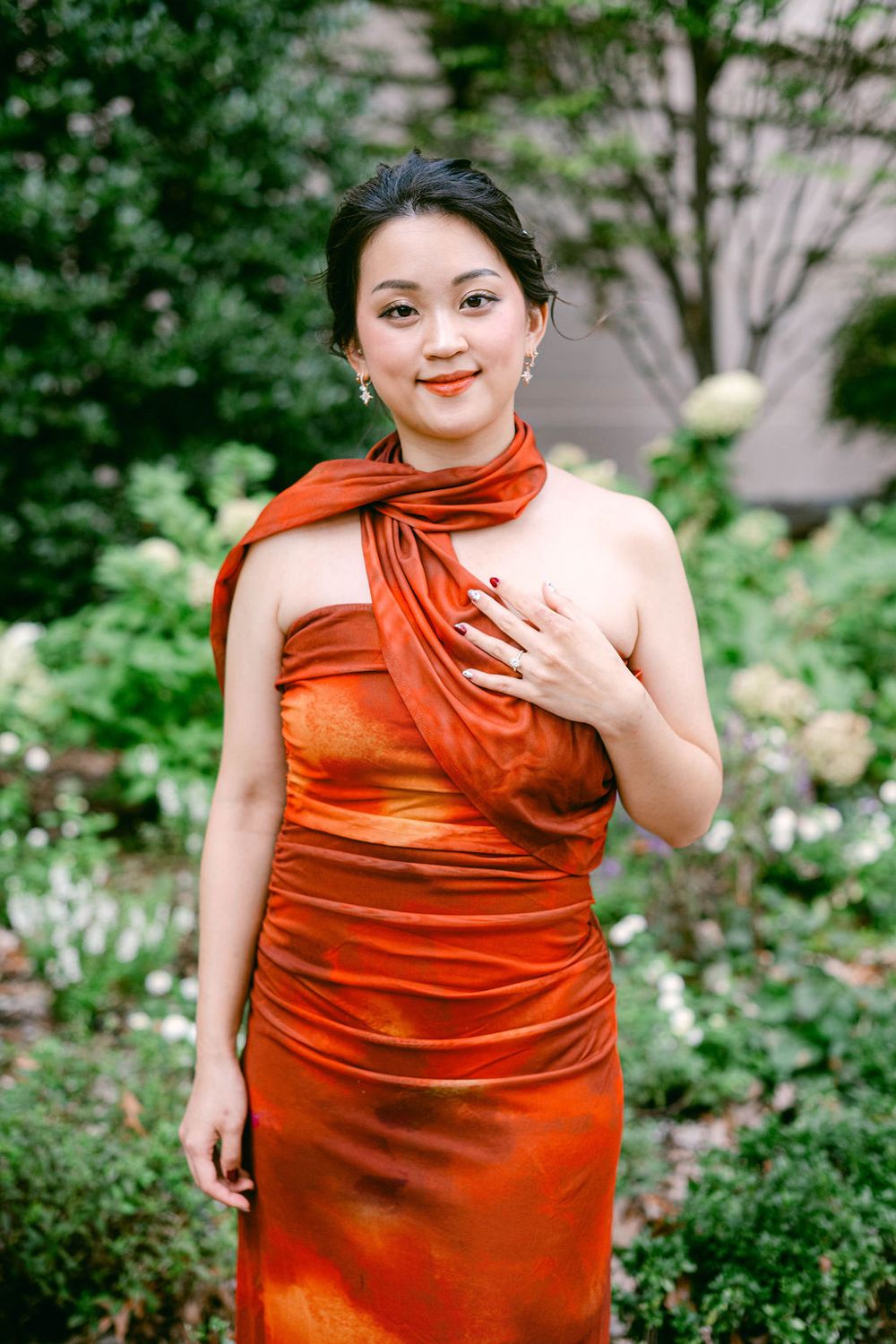 A vibrant orange dress stands out against lush greenery in an outdoor portrait session.