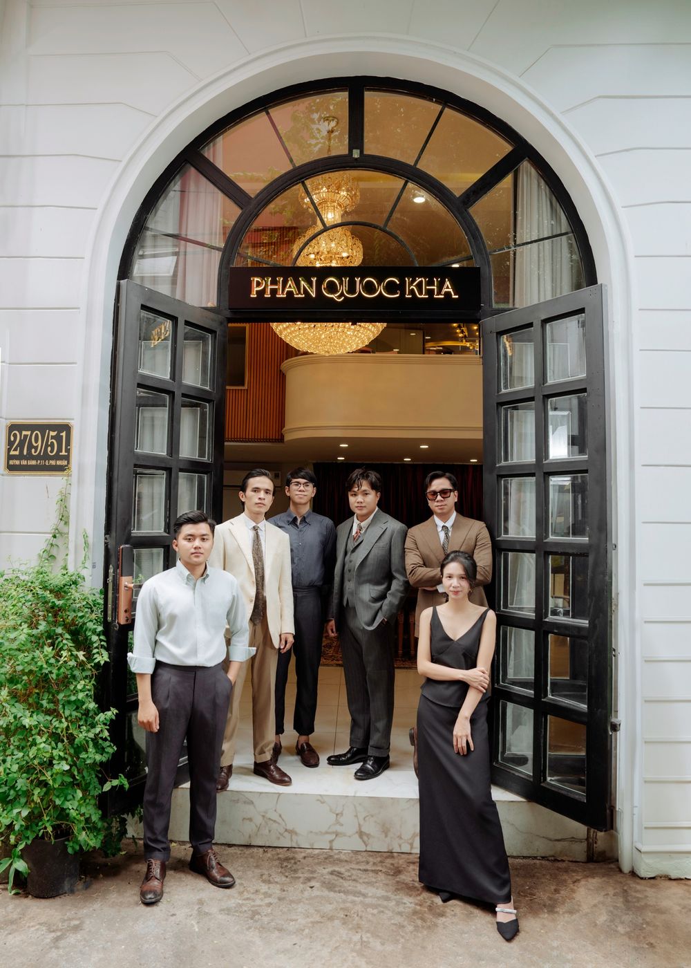 Professional team of five men and one woman posing at entrance of Phan Quoc Kha boutique studio.
