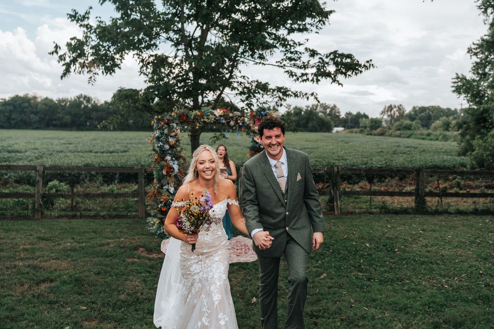 Romantic couple embracing in a lush green field during a wedding photo session.