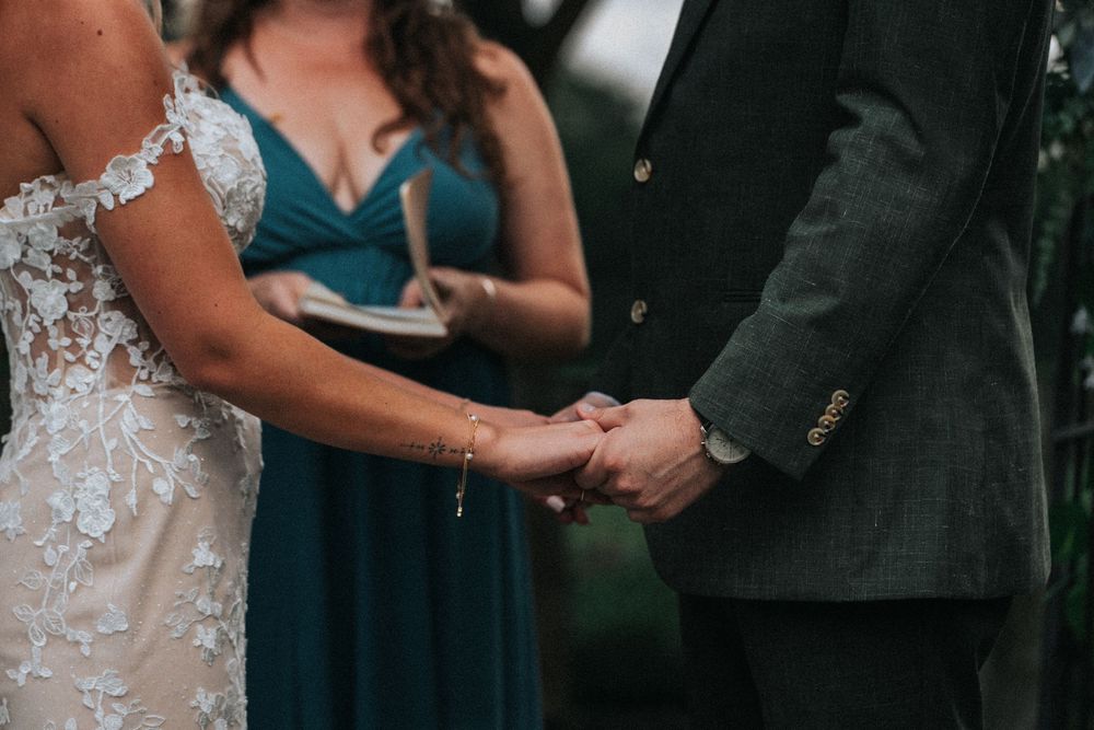 Wedding ceremony guests seated outdoors with bridesmaids in rust-colored dresses and elegant white decor.