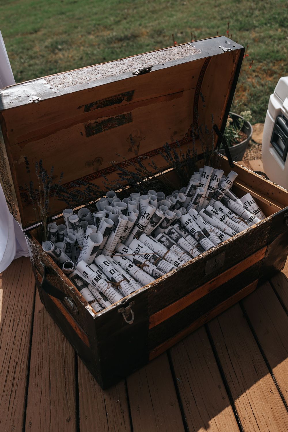 Wooden trunk filled with numerous rolled paper scrolls or documents arranged in rows on a wooden deck.