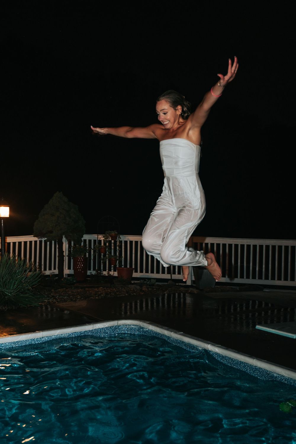 Sequence of a bride in white dress jumping into a swimming pool at night.