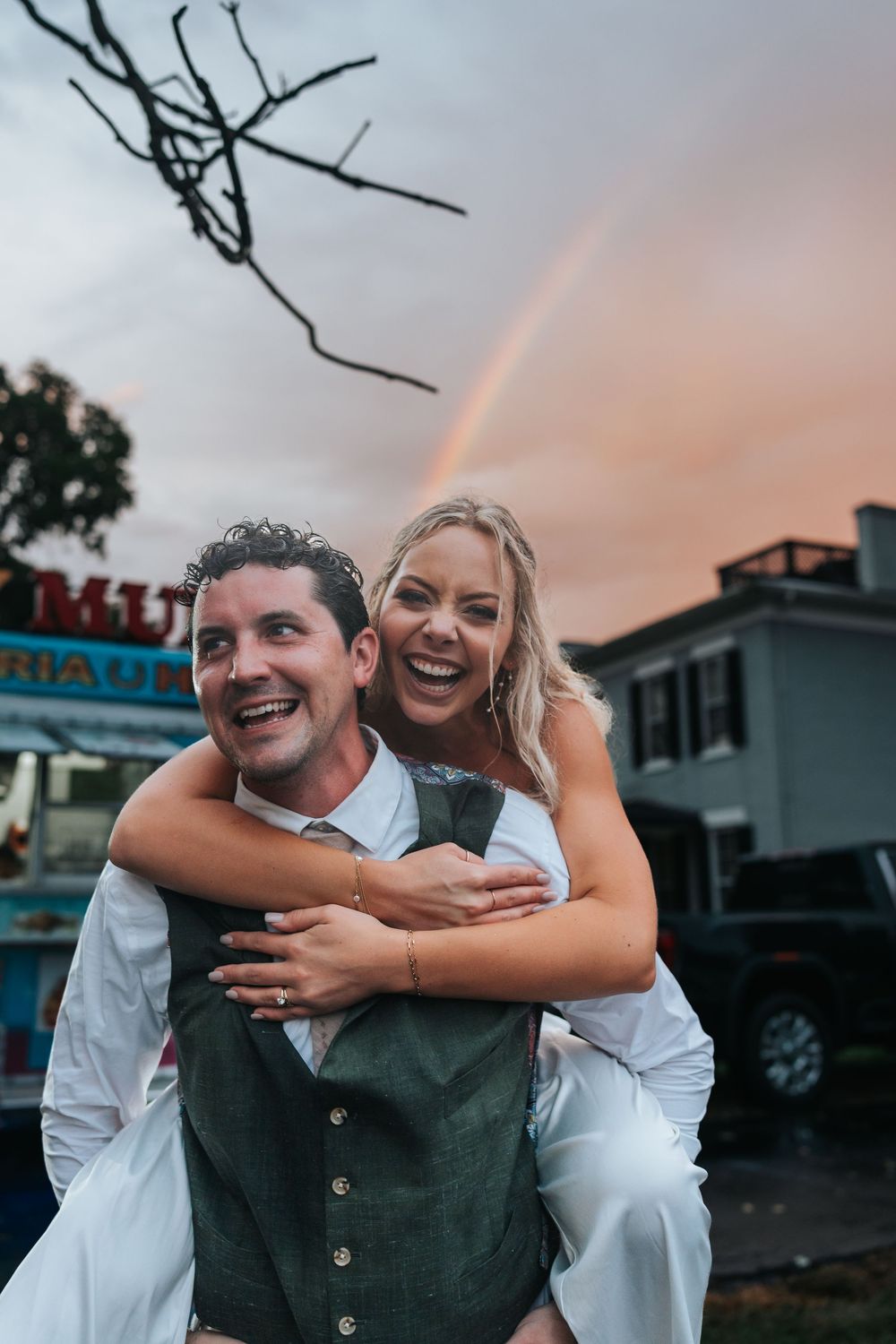A joyful couple embraces and laughs together during sunset at an outdoor location.