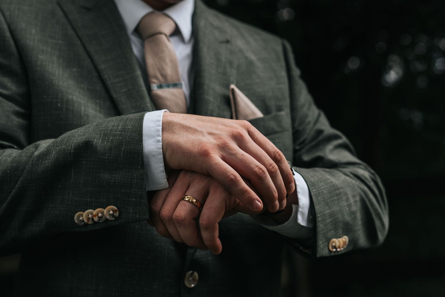 Close-up view of hands adjusting a suit jacket sleeve showing attention to formal business attire details.