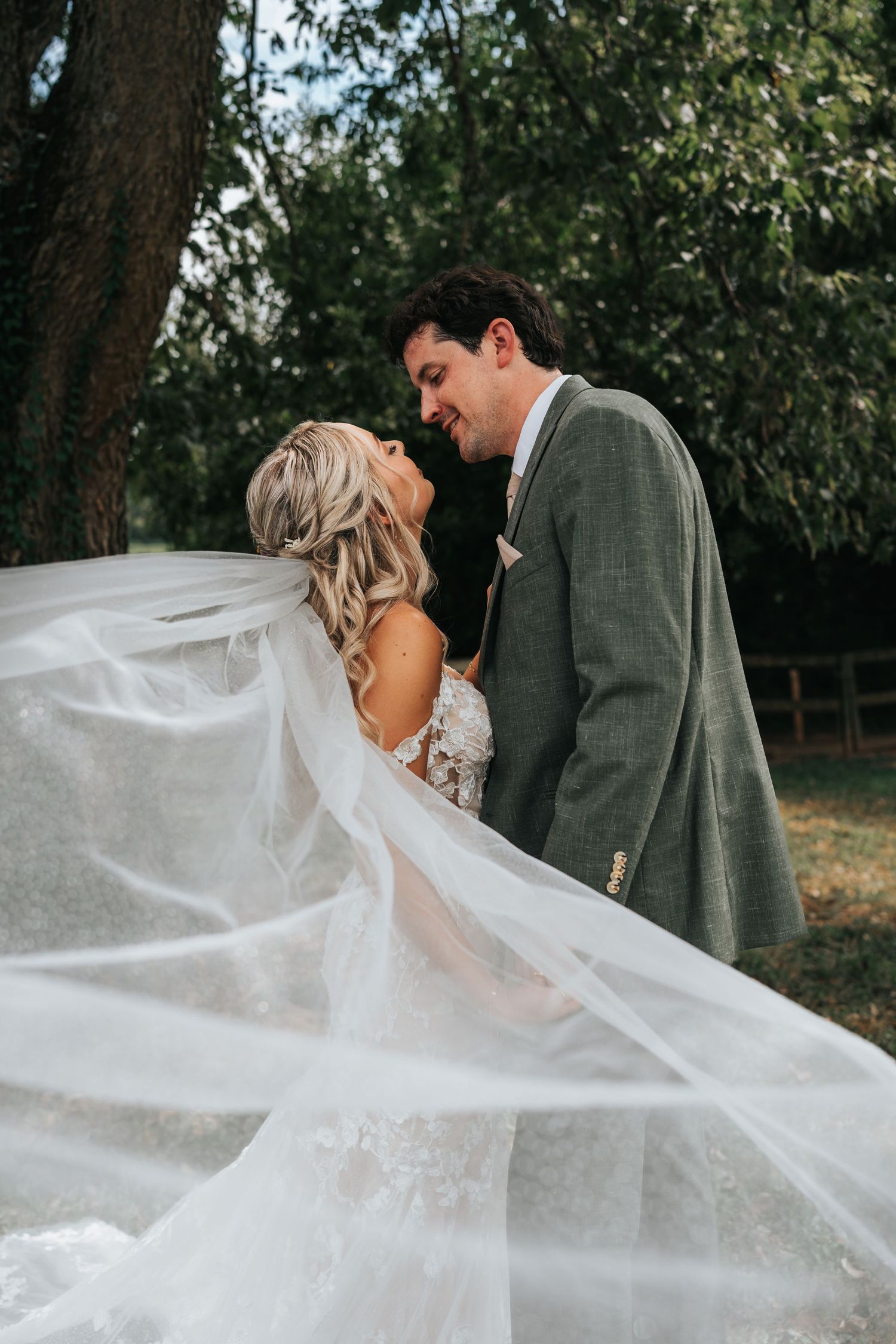 A romantic wedding couple embraces as the bride's long white veil flows dramatically in the breeze through multiple frames.