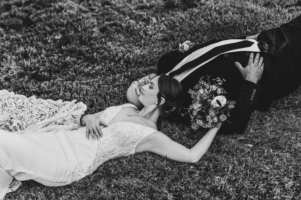 an editorial pose of the bride laying next to her husband after their wedding ceremony