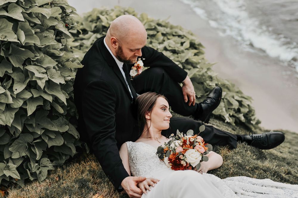 a bride and her groom cuddle on the bank of the river in weatherford