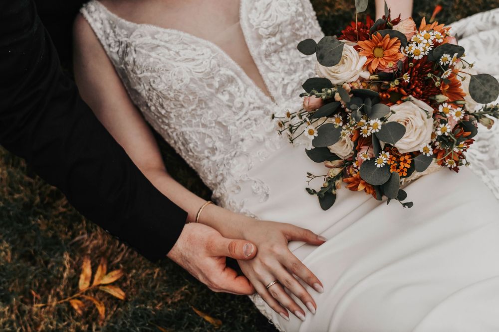a close up of a bride and groom holding hands next to the brides bouquet