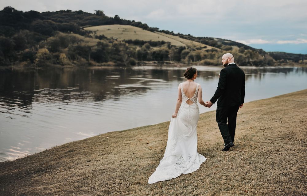 a dramatic and powerful moment of the bride and groom candidly walking towards the river at their wedding venue