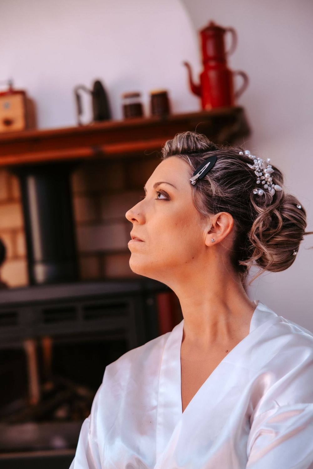 A person in a white robe sits with their hair up in an elegant style, looking upward in a contemplative pose.