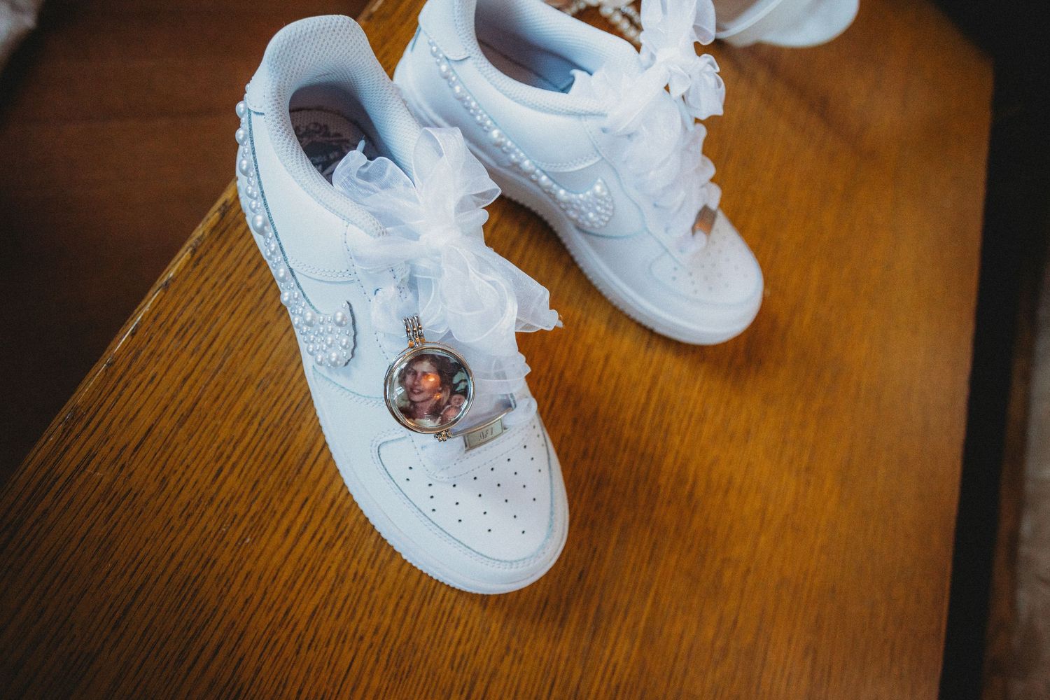 White Nike Air Force 1 sneakers on a wooden floor with laces being tied in a progressive sequence.