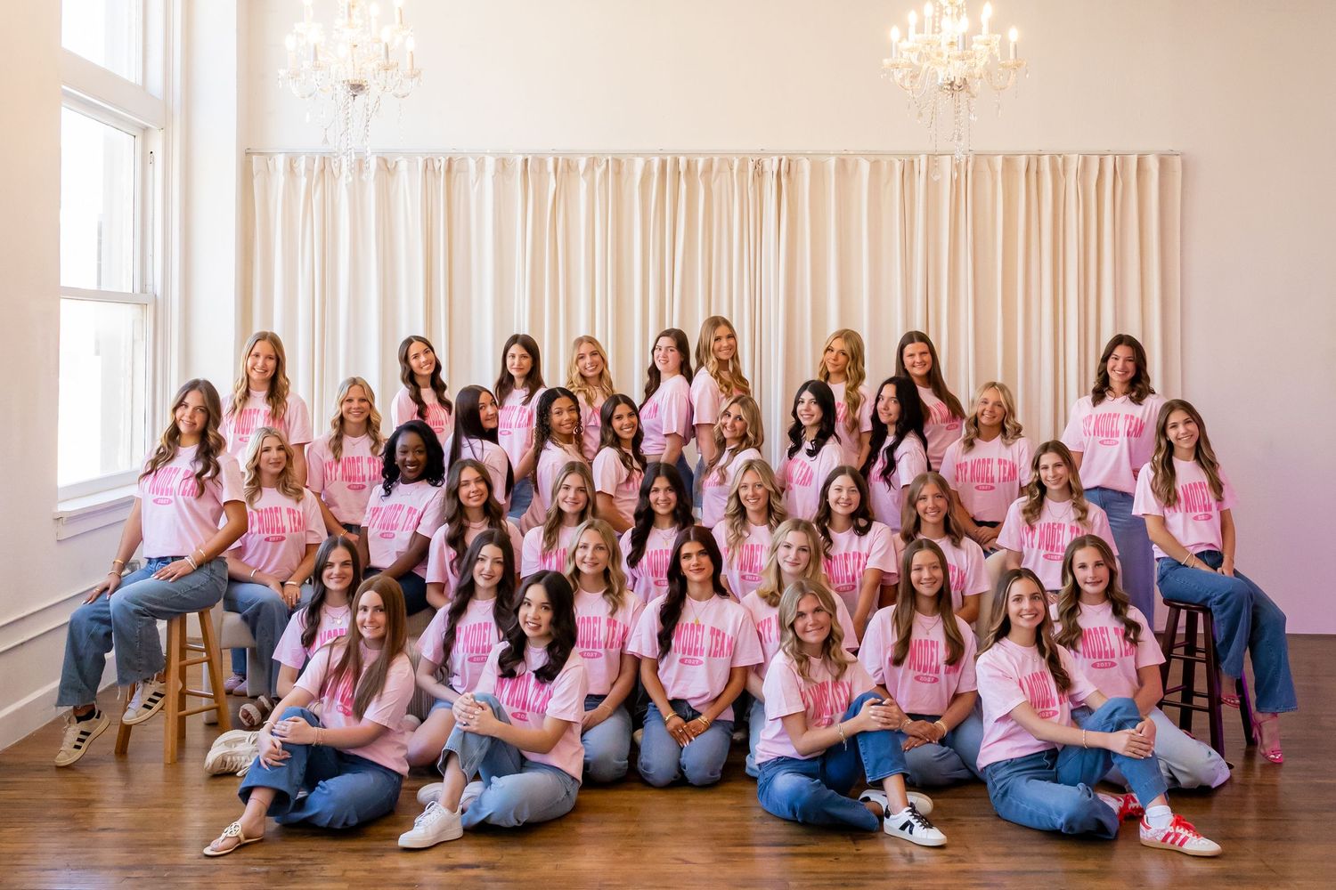 Students gathered in matching outfits for a group photo in a modern indoor setting.