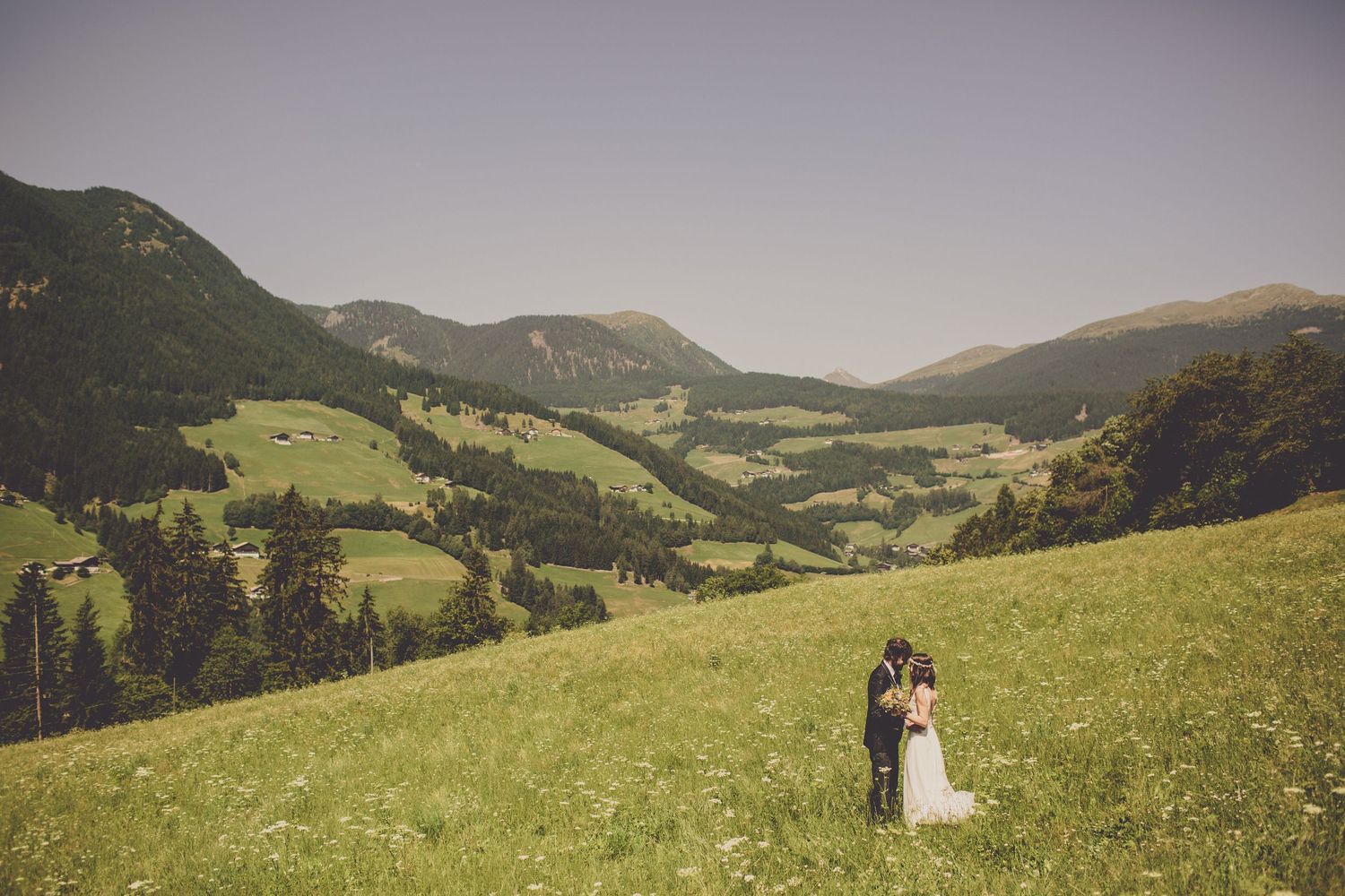 Bride and groom standing in alpine meadow with Dolomites landscape in South Tyrol