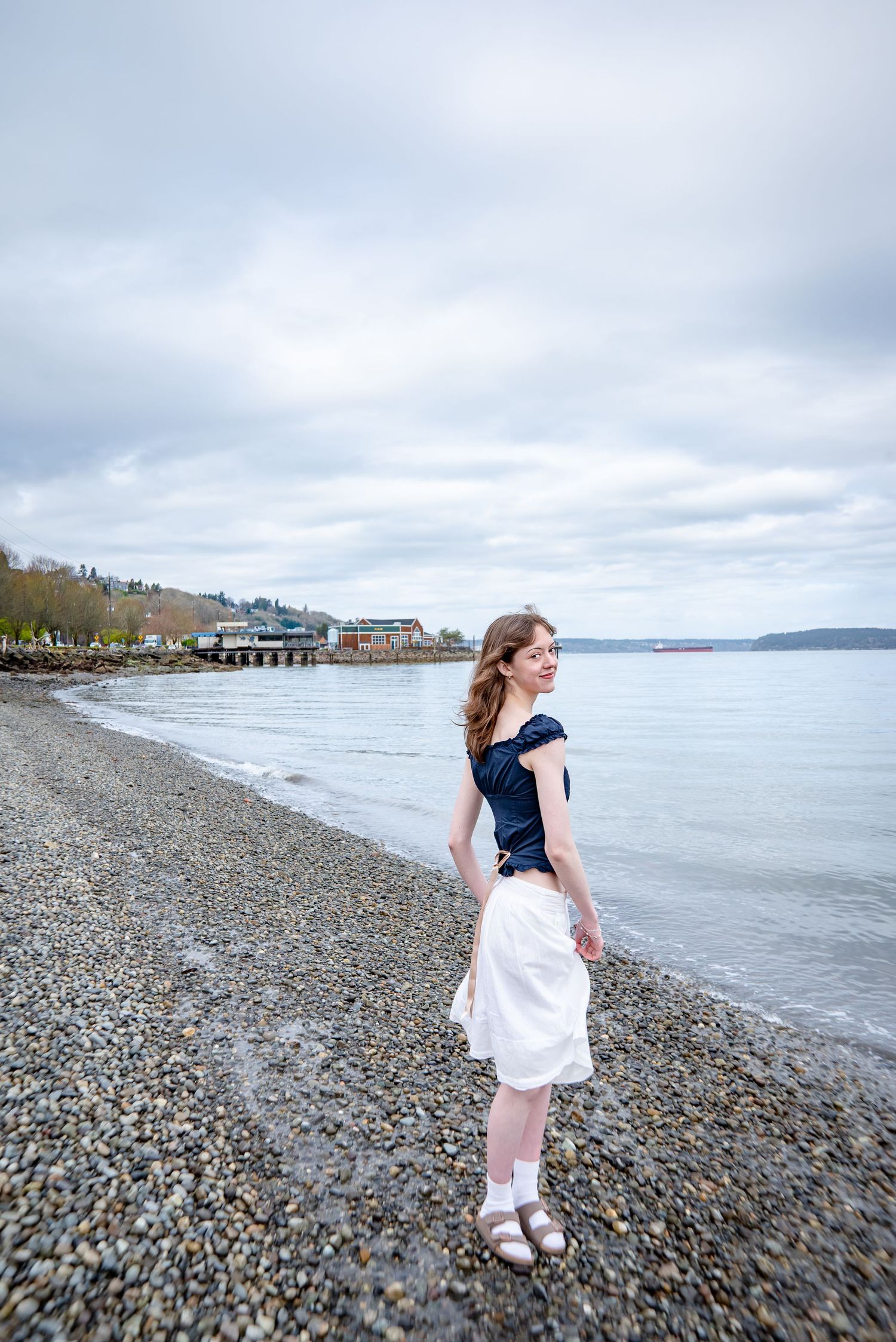 High school senior walking along beach at Tacoma waterfront park, Dickman Mill Park, for graduation photos.