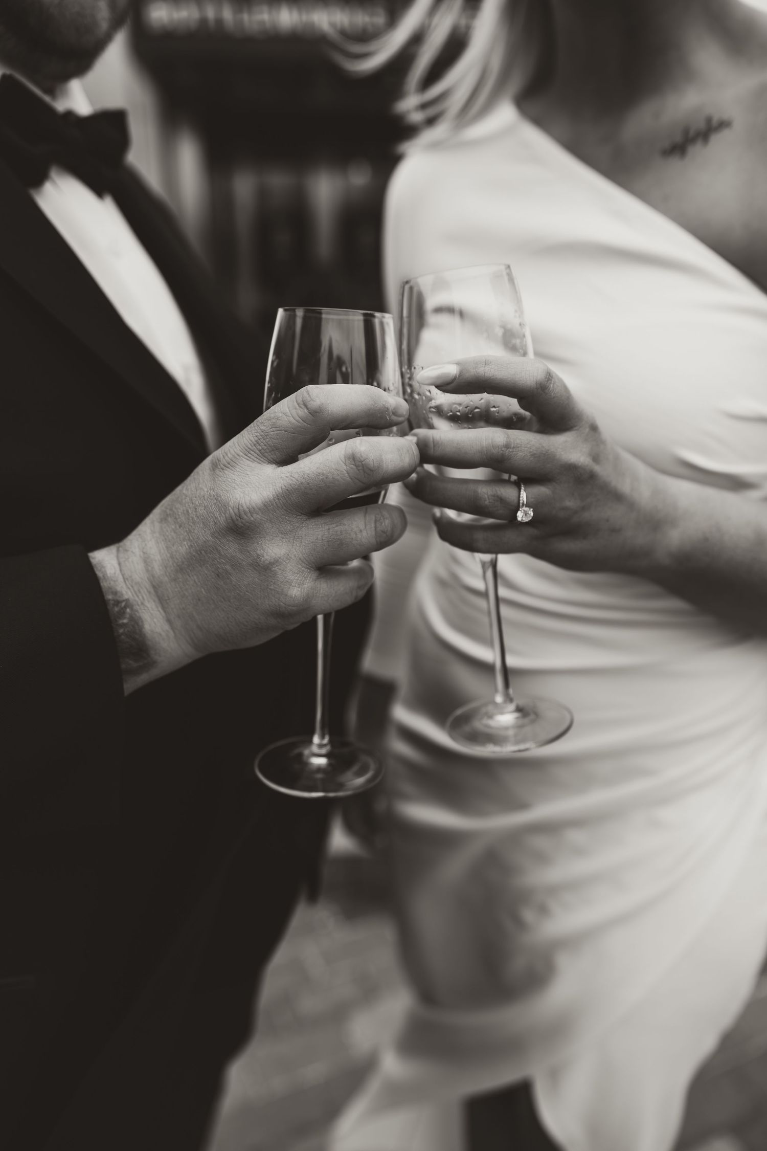 Black and white engagement photo, couple holding wine glasses, engagement ring in focus, Indianapolis engagement session.