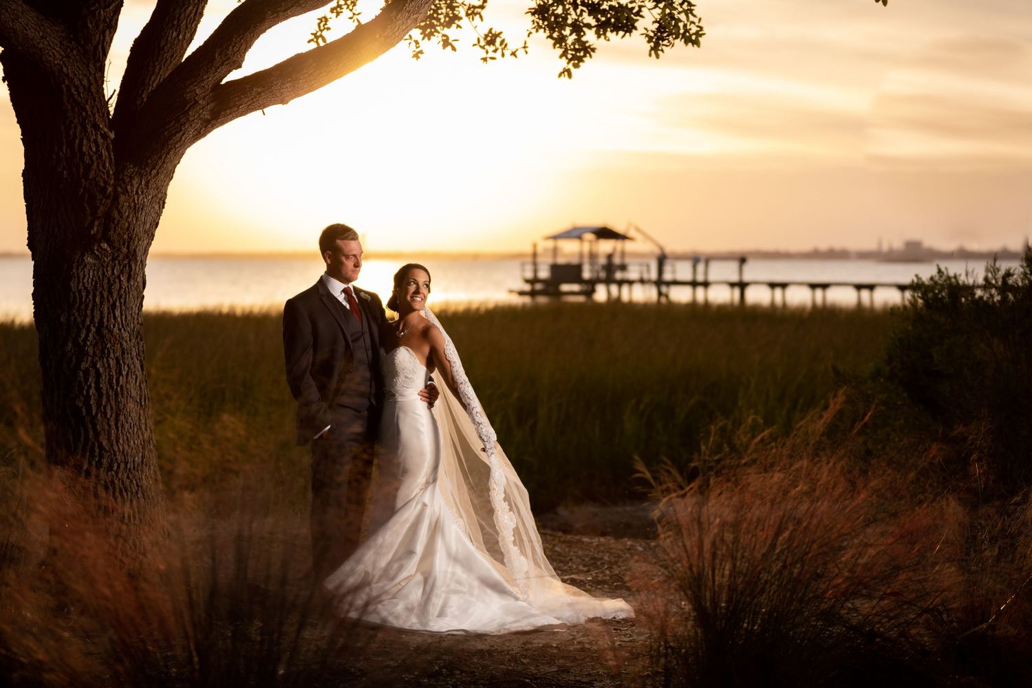 A silhouetted couple stands together against a dramatic orange and purple sunset sky with dark clouds.