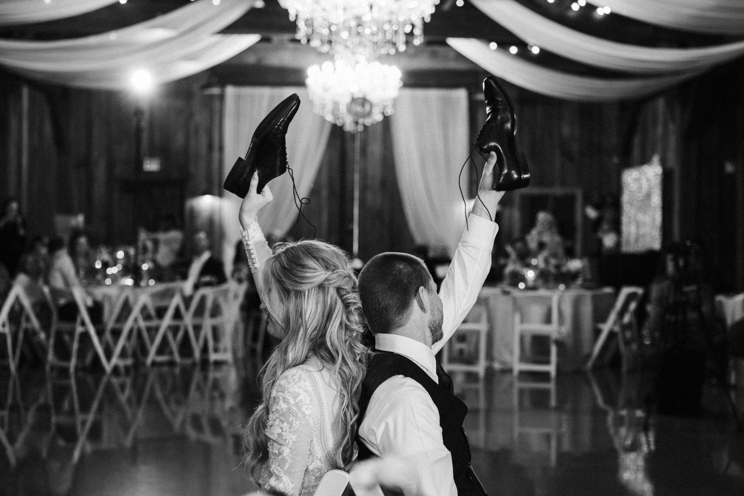 A romantic first dance between newlyweds under elegant chandeliers at an evening wedding reception.