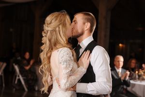 A couple shares a romantic dance at their wedding reception in a dimly lit venue.