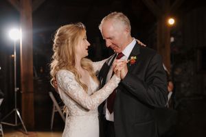 A couple shares a romantic dance moment at an evening wedding reception with warm lighting and elegant decor.