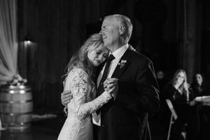 Couple in formal wedding attire share a romantic dance together during their reception celebration.