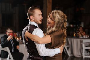 A couple dances together in a dimly lit reception venue with elegant decor and ambient lighting.