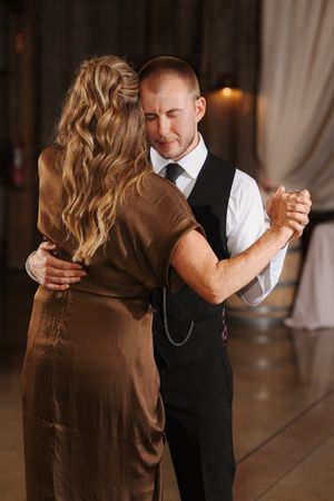 Dancing couple sharing an intimate moment on a polished wooden dance floor at a wedding reception.