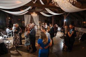 Elegant wedding reception venue decorated with white fabric draping and chandeliers creates a romantic dance floor atmosphere.