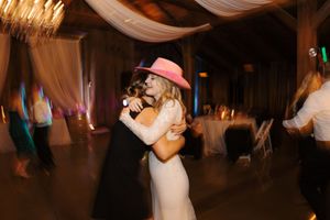 Couple dancing together at an elegant wedding reception under draped fabric ceiling decorations.