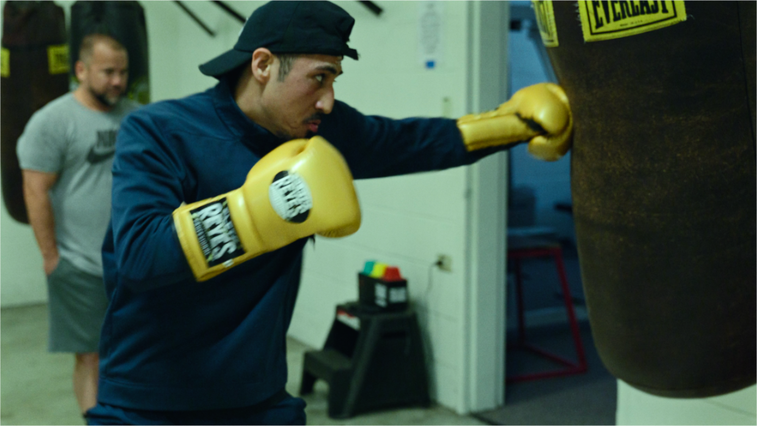 A boxer practicing punches on a heavy bag in a gym with yellow boxing gloves.