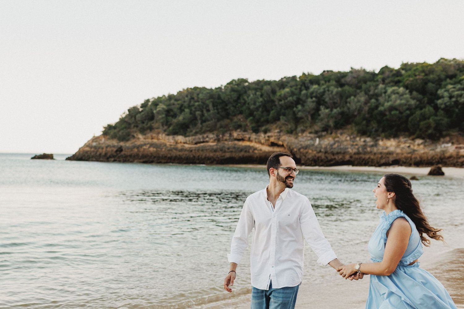 Natural pre-wedding photos in Setúbal with couple holding hands at Praia dos Galapinhos