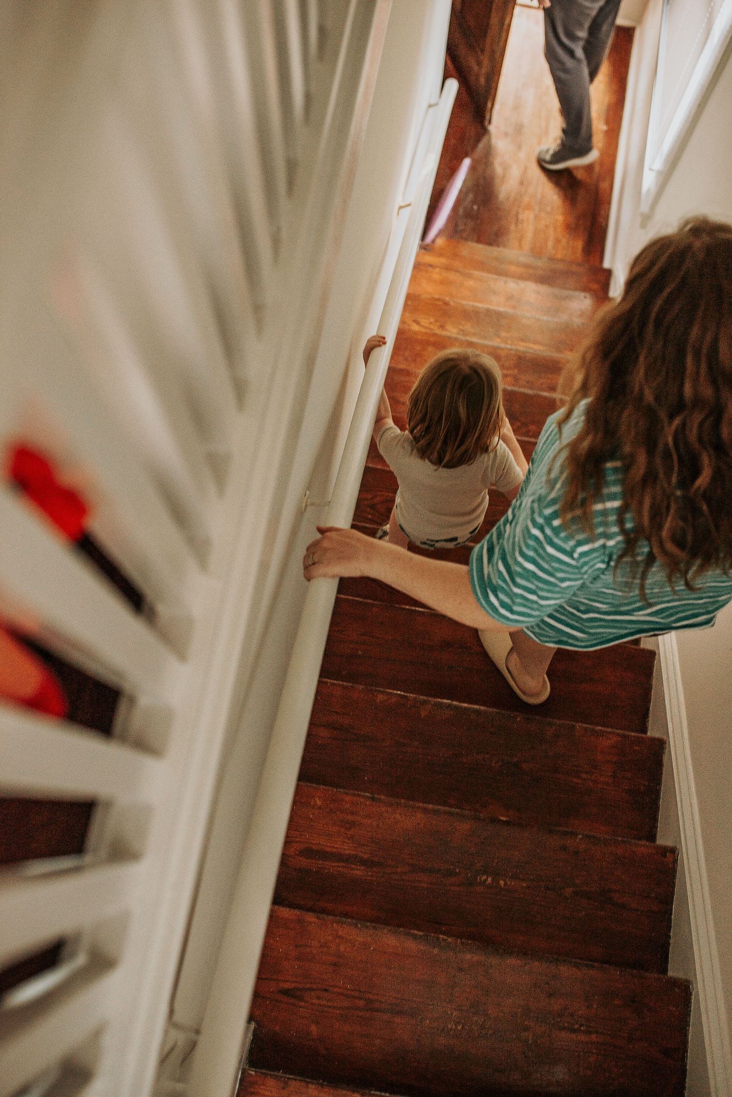 A sequence of four photos showing a person walking down wooden stairs in a white-walled hallway.