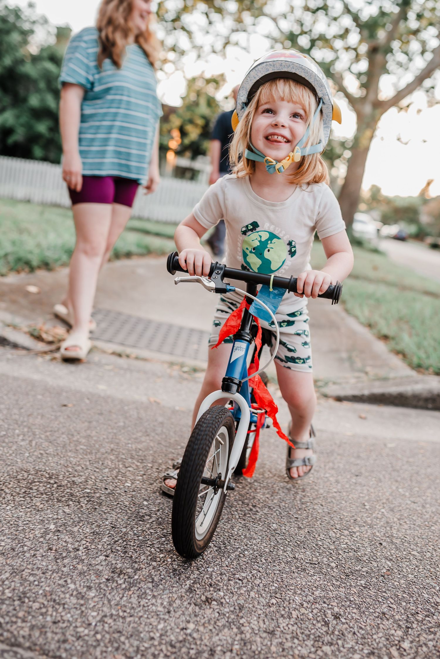 Young child rides orange balance bike on gravel path while learning essential cycling skills during outdoor playtime.
